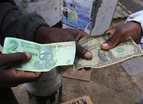 Illegal money changers pose while exchanging a new Zimbabwe bond note (L) and U.S. dollar notes in the capital Harare, Zimbabwe, November 28, 2016. PHOTO BY REUTERS/Philimon Bulawayo