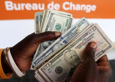 An illegal foreign currency trader poses counting notes at a local bus station in the capital Harare, Zimbabwe, November 18, 2016. PHOTO BY REUTERS/Philimon Bulawayo