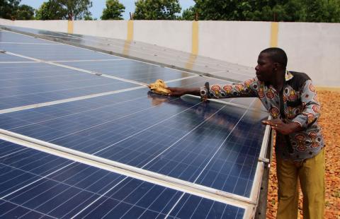 A technician cleans solar panels, part of the BBOXX and EDF solar energy system used to provide electricity to Sikpe Afidegnon village, Togo, May 16, 2019. PHOTO BY REUTERS/Noel Kokou Tadegnon