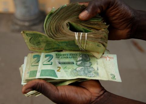 A street vendor poses as he displays bond notes, before the introduction of new currency in Harare, Zimbabwe, November 11, 2019. PHOTO BY REUTERS/Philimon Bulawayo