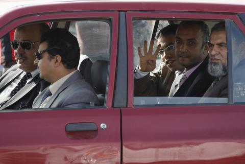 A lawyer of the Muslim Brotherhood and ousted Egyptian President Mohamed Mursi gestures with four fingers as he arrives at the police academy