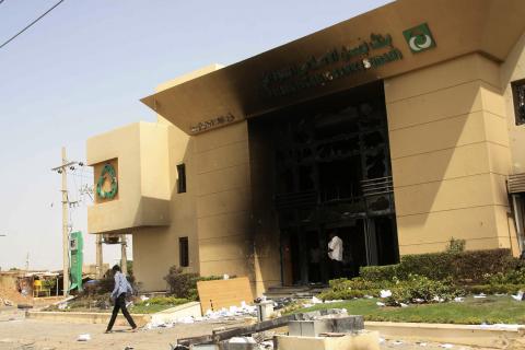 A man passes a burnt bank during protests over fuel subsidy cuts in Khartoum