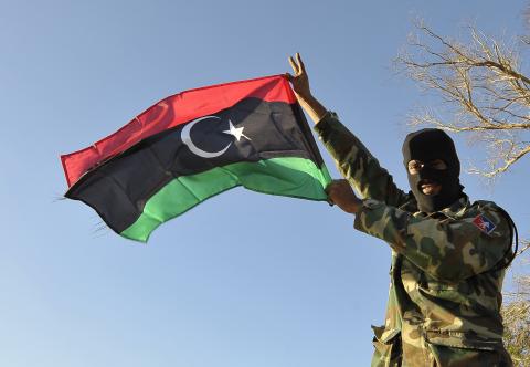 A member of the Libyan army's Thunderbolt Brigade flies the Libyan flag