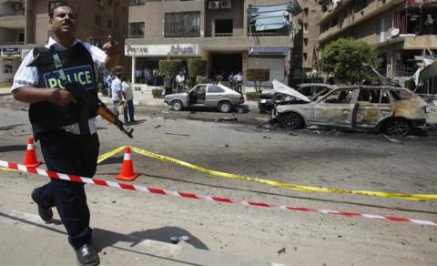 A policeman asks members of the media and onlookers to move back at the site of an explosion near the house of Egypt's interior minister at Cairo's Nasr City district