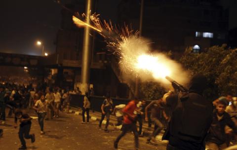 A riot police officer fires tear gas during clashes between anti-Mursi protesters, and members of the Muslim Brotherhood and ousted Egyptian President Mohamed Mursi supporters