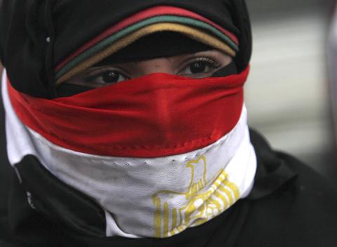 A woman, with the national flag covering part of her face, takes part in a protest rally against then Egyptian President Mohamed Mursi and members of the Muslim Brotherhood