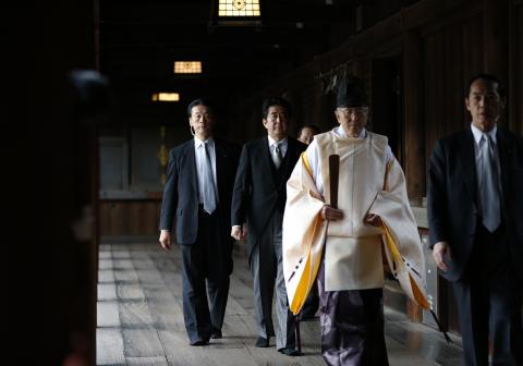 Japan's Prime Minister Shinzo Abe (2nd L) is led by a Shinto priest as he visits Yasukuni shrine in Tokyo