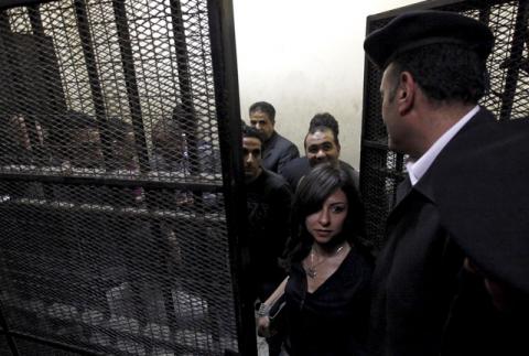 Activists, accused of working for unlicensed non-governmental organizations (NGOs) and receiving illegal foreign funds, stand in a cage during the opening of their trial in Cairo, March 8, 2012. PHOTO BY REUTERS/Mohamed Abd El Ghany