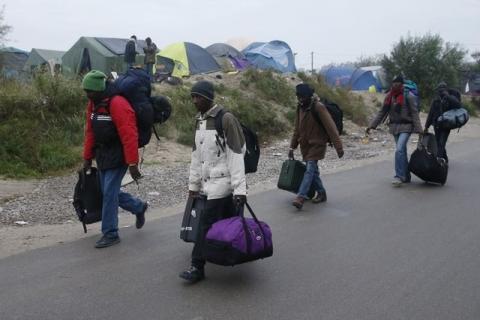 Migrants with their belongings walk past tents at the start of their evacuation and transfer to reception centers in France, and the dismantlement of the camp called the "Jungle" in Calais, France, October 24, 2016. PHOTO BY REUTERS/Pascal Rossignol