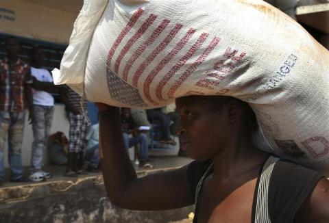 A displaced refugee woman carries a rice bag after receiving it as humanitarian aid at the airport outside the capital Bangui