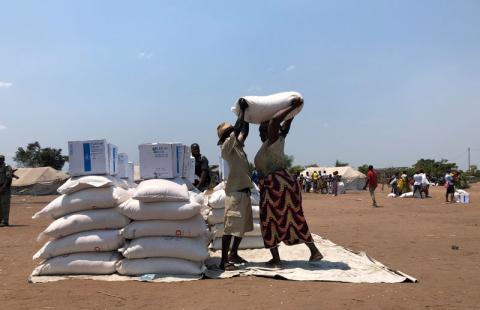 A man helps a woman lift a bag of aid during a distribution for victims of Cyclone Idai at a camp in Guara Guara, outside Beira, Mozambique, October 8, 2019. PHOTO BY REUTERS/Emma Rumney