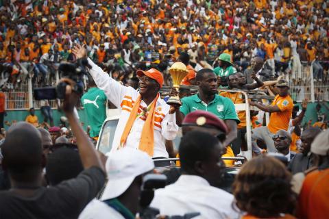 Ivory Coast's President Alassane Ouattara (centre L) waves as he holds the African Nations Cup trophy with Ivory Coast's soccer team captain Yaya Toure, at the Felix Houphouet-Boigny stadium in Abidjan, February 9, 2015. PHOTO BY REUTERS/Thierry Gouegnon