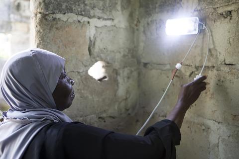 Amina Shamata, a teacher at Barefoot College, Zanzibar, installs a solar light in a home in Knyasini Bondini village, Zanzibar, 24 October 2018. PHOTO BY Thomson Reuters Foundation/Nicky Milne