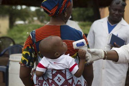 A health worker checks the temperature of a baby entering Mali from Guinea at the border in Kouremale, October 2, 2014. PHOTO BY REUTERS/Joe Penney