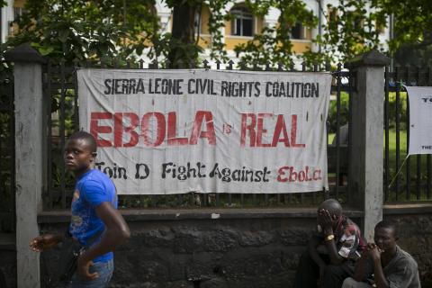 A man walks past a banner about Ebola in Freetown, Sierra Leone, December 16, 2014. PHOTO BY REUTERS/Baz Ratner