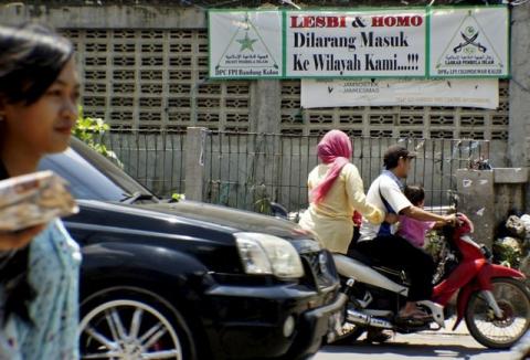 People drive a motorcycle past a banner put up by the hardline Islamic Defenders Front calling for gay people to leave the Cigondewah Kaler area in Bandung, Indonesia West Java province, January 27, 2016. PHOTO BY REUTERS/Agus Bebeng