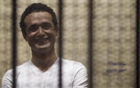 Egyptian activist Ahmed Douma smiles from behind bars during his trial at the New Cairo court, on the outskirts of Cairo