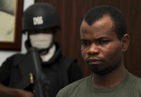 Kabiru Sokoto, a suspect in a Christmas Day bomb attack of St. Theresa Catholic Church in Madalla near Nigeria's capital, is guarded by a security official inside the state security service office in the capital Abuja