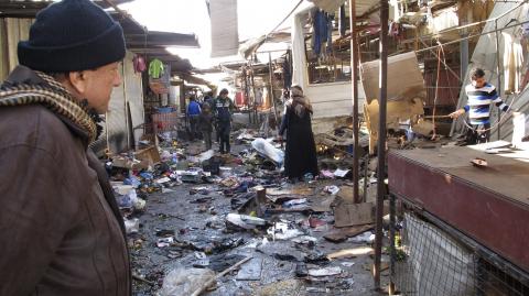 A man looks at the site of bomb attack at a marketplace in Baghdad's Doura District