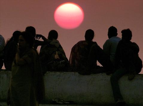 A group of people sit on a sea-wall watching the sunset over the Arabian Sea in Bombay in this March 3, 2001. PHOTO BY REUTERS/Stringer