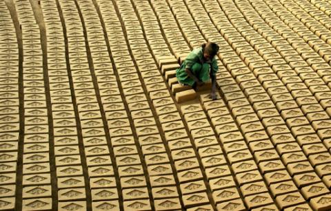 An Indian child labourer arranges bricks at a brick factory in Tharvai village, about 35 km (22 miles) from the northern Indian city of Allahabad, February 21, 2006. PHOTO BY REUTERS/Jitendra Prakash