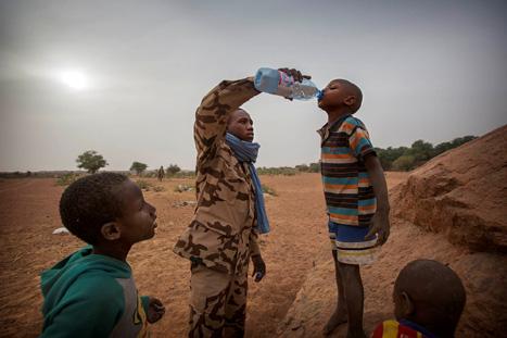 A member of MINUSMA Chadian contingent gives water to a boy in Kidal, Mali, December 17, 2016. PHOTO BY REUTERS/MINUSMA/Sylvain Liechti