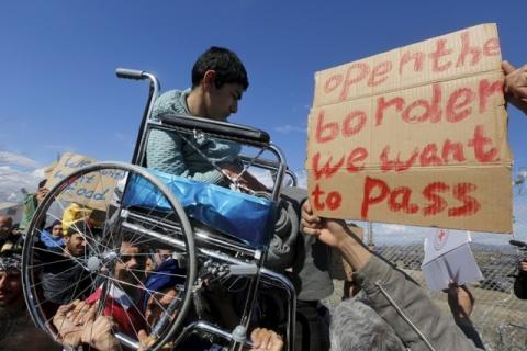 Stranded refugees and migrants lift a wheelchair-bound boy during a protest next to the Greek-Macedonian border fence near the Greek village of Idomeni, February 27, 2016. PHOTO BY REUTERS/Yannis Behrakis