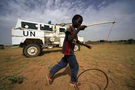 A boy plays in front of UNAMID peacekeepers stand guard as a delegation of Ambassadors of European Union to Sudan visits a women development program centre funded by World Food Programme (WFP) at Shagra village in North Darfur October 18, 2012. PHOTO BY REUTERS/Mohamed Nureldin Abdallah