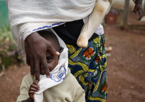 An internally displaced Muslim boy stands in front of his mother who is carrying another child in the town of Boda