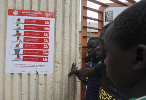 Boys stand next to a poster, pertaining to the Ebola virus, during a training session by Sierra Leone's national soccer team at the Felix Houphouet Boigny stadium in Abidjan