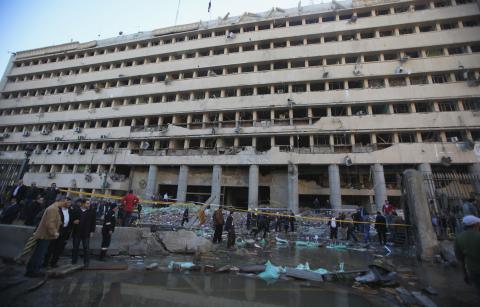 Police officers and people gather in front of the damaged Cairo Security Directorate, which includes police and state security, after a bomb attack in downtown Cairo