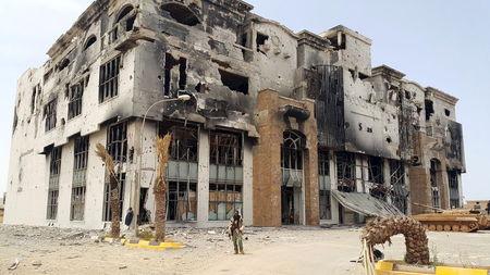 A member of the Libyan pro-government forces stands in front of the ruins of a shopping mall in Benghazi, Libya, May 21, 2015. PHOTO BY REUTERS/Stringer