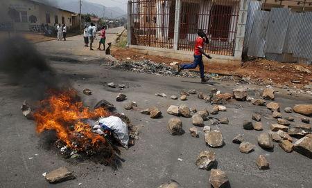 A man runs past a burning barricade on a rock strewn street in Bujumbura's Niyakabiga district on Presidential election day in Burundi, July 21, 2015. PHOTO BY REUTERS/Mike Hutchings