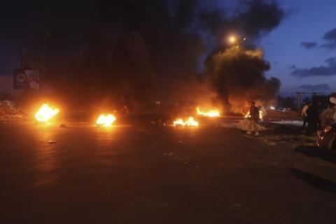 Burning obstacles are seen along a road leading to the airport in Tripoli