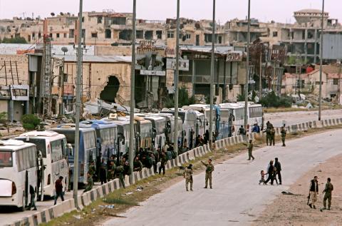 Syrian forces of President Bashar al Assad are seen around buses carry civilian and rebels outside Harasta in eastern Ghouta in Damascus, Syria, March 23, 2018. PHOTO BY REUTERS/ Omar Sanadiki