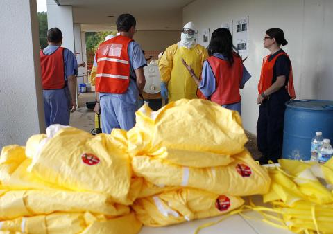 Centers for Disease Control and Prevention (CDC) instructors give guidance on decontamination to health care workers as personal protection equipment lies on a table in the foreground, in preparation for the response to the current Ebola outbreak, during a CDC safety training course in Anniston, Alabama