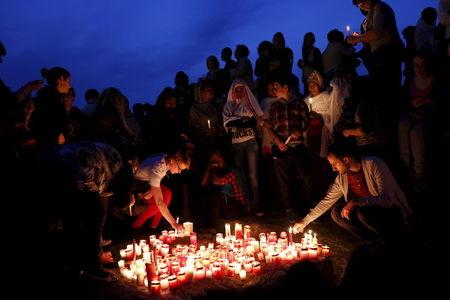 People place candles on the shoreline rocks as they take part in a vigil to commemorate migrants who died at sea in Sliema, outside Valletta, April 22, 2015. PHOTO BY REUTERS/Darrin Zammit Lupi