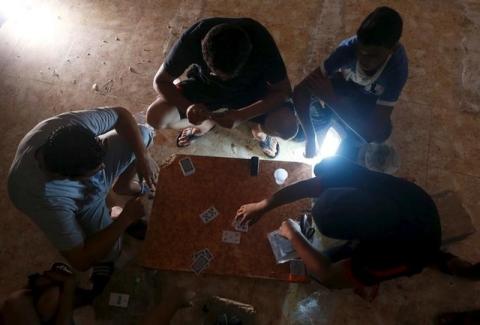 Men play cards in the light of a lamp as the city witnesses a break in electricity for long hours because of clashes taking place in the city between pro-government forces and the Shura Council of Libyan Revolutionaries in Benghazi, Libya, August 6, 2015. PHOTO BY REUTERS/Esam Omran Al-Fetori