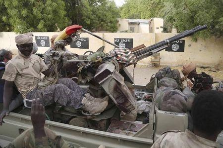 Chadian soldiers drive past flags painted by Boko Haram militants in the recently retaken town of Damasak, Nigeria, March 18, 2015. PHOTO BY REUTERS/Emmanuel Braun