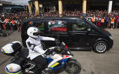 Townsmen line the streets as a military policeman escorts a hearse containing the flag draped coffin of former South African President Nelson Mandela through the center of Mthatha, South Africa