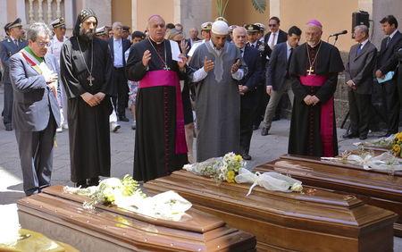 Local civil and religious representatives pray in front of the coffins of 13 unidentified migrants who died in the April 19, 2015 shipwreck, during an inter-faith funeral service in Catania, Italy, July 7, 2015. PHOTO BY REUTERS/Antonio Parrinello