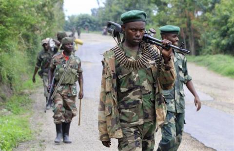 Congolese M23 rebels carry their weapons as they patrol near Rushuru