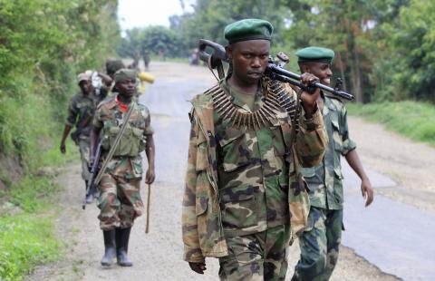 Congolese M23 rebels carry their weapons as they patrol near Rushuru