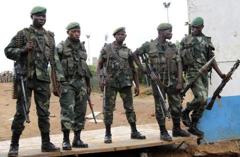 Congolese soldiers stand guard as they watch residents blocking a road as they protest the killings of two locals near Beni in North Kivu province, October 22, 2014. PHOTO BY REUTERS/Kenny Katombe