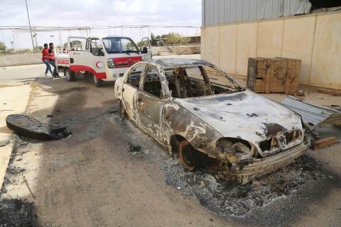 Members of the Libyan Red Crescent remove corpses near a damaged vehicle at the site of clashes between pro-government forces backed by locals and both the Shura Council of Libyan Revolutionaries and Islamist group Ansar al-Sharia in Benghazi, October 21, 2014. PHOTO BY REUTERS/Stringer