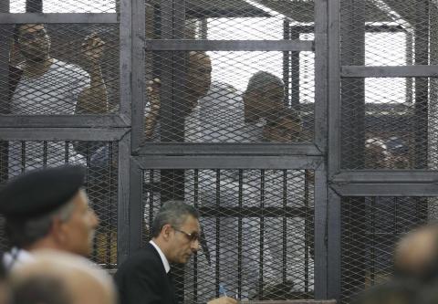 Peter Greste, Mohamed Fahmy and Baher Mohamed (2nd L to R) stand behind bars with other defendants as they listen to the ruling at a court in Cairo