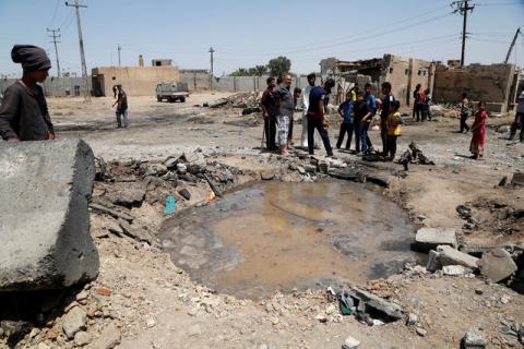 People gather around a crater after a suicide bomb attack in a southeastern suburb of Baghdad, Iraq, April 30, 2016. PHOTO BY REUTERS/Wissm al-Okili