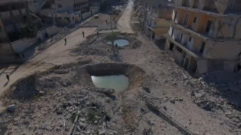 People stand near craters and damaged buildings in a rebel-held area of Aleppo, Syria in this still image from drone footage taken on September 27, 2016. PHOTO BY REUTERS