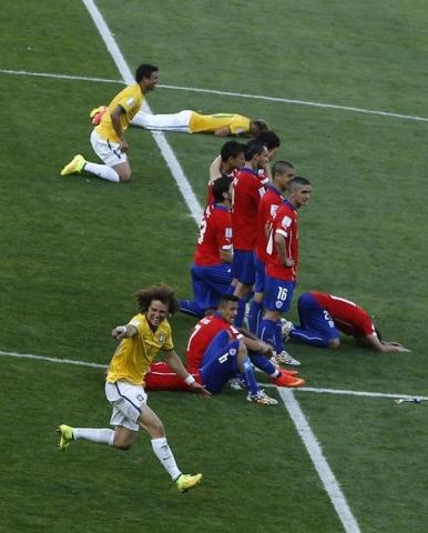 Brazil's David Luiz celebrates past Chile's players after Chile's Gonzalo Jara (unseen) missed the decisive penalty shot during the penalty shootout in their 2014 World Cup round of 16 soccer game at the Mineirao stadium in Belo Horizonte June 28, 2014. REUTERS/Leonhard Foeger