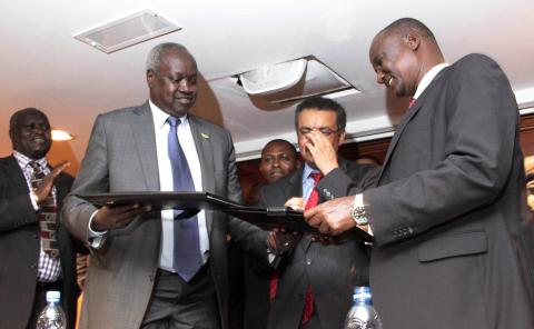 South Sudan's leader of the government's delegation Nhial Deng Nhial (L) exchanges a signed ceasefire agreement with the head of the rebel delegation General Taban Deng Gai (R) to end more than five weeks of fighting